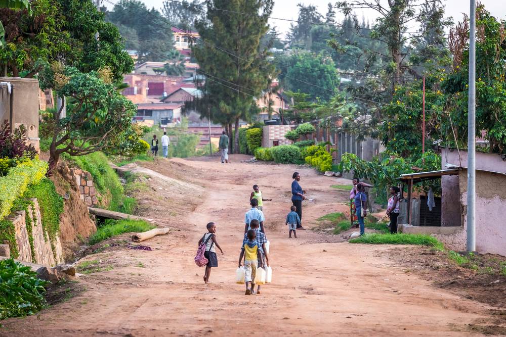 在吉佳利(Kigali)一個住宅區的公共汲水區，孩童提著裝滿水的水桶回家。