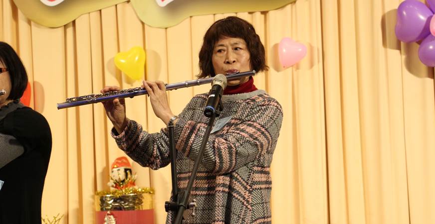 65歲的黃淑嬌(照片中吹奏者)與社區長笛班的同學賴文玲一起以長笛吹奏「夜空」、「可愛的玫瑰花」等曲目展現孝心