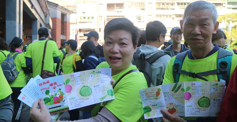 弟兄姊妹手拿单张，裡面介绍马偕宣教士带来台湾的蔬菜。