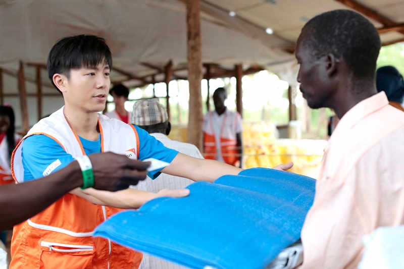 在难民接待中心内，韦礼安和刘以豪帮忙世界展望会工作人员分发热食及肥皂、毛毯、防水布等生活物资给难民。