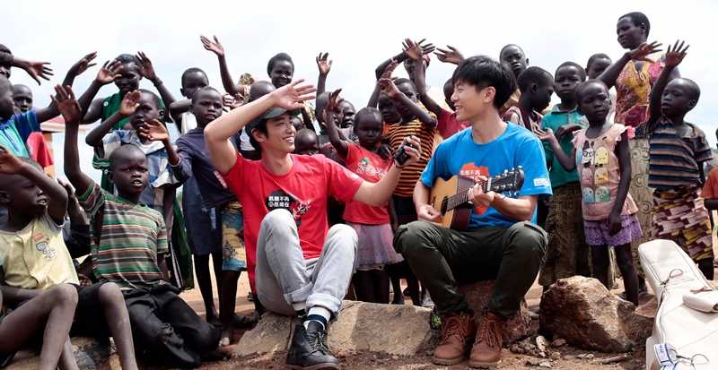 在世界展望會於畢迪畢迪難民屯墾區開設的兒童關懷中心裡，韋禮安彈著吉他，與劉以豪一起帶領小朋友開心地拍手唱歌。